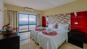 A hotel room with two beds, a desk, and a view of the sea. - Grand Muthu Oura View Beach Club (Albufeira)