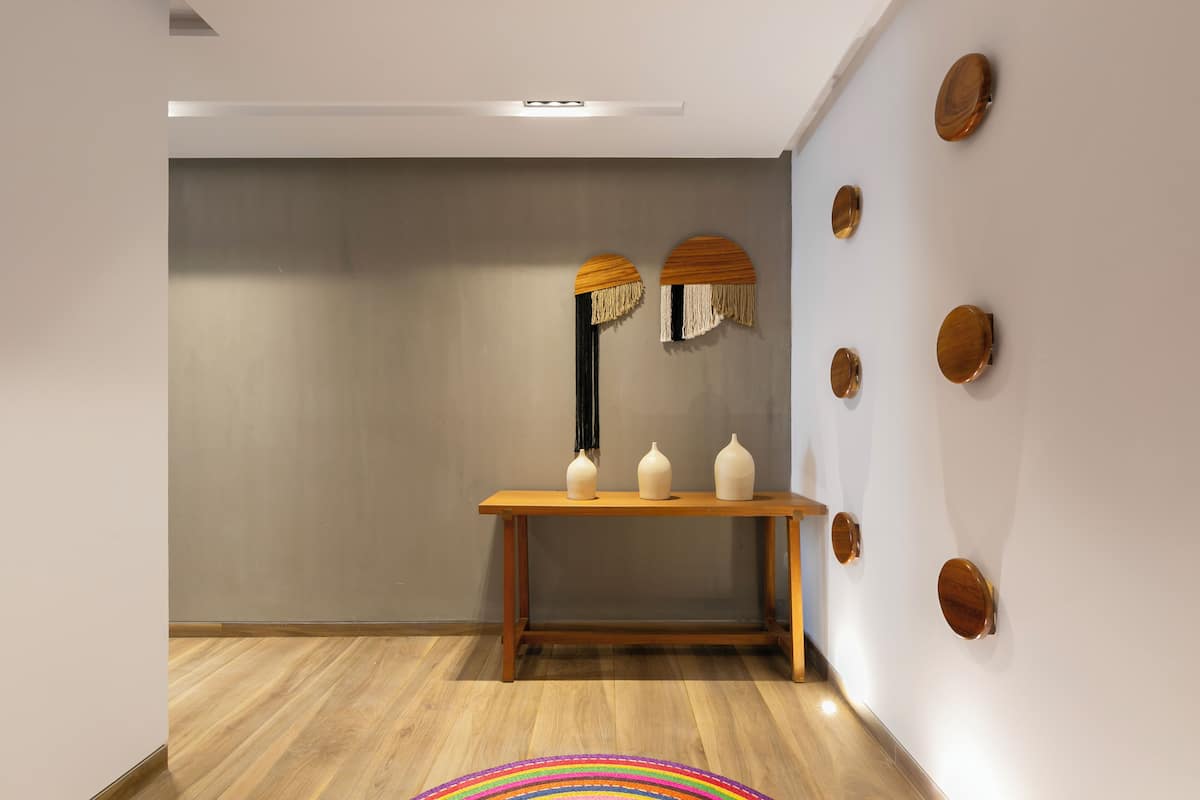A modern interior with a wooden table, three white vases, and wall-mounted wooden decorations.