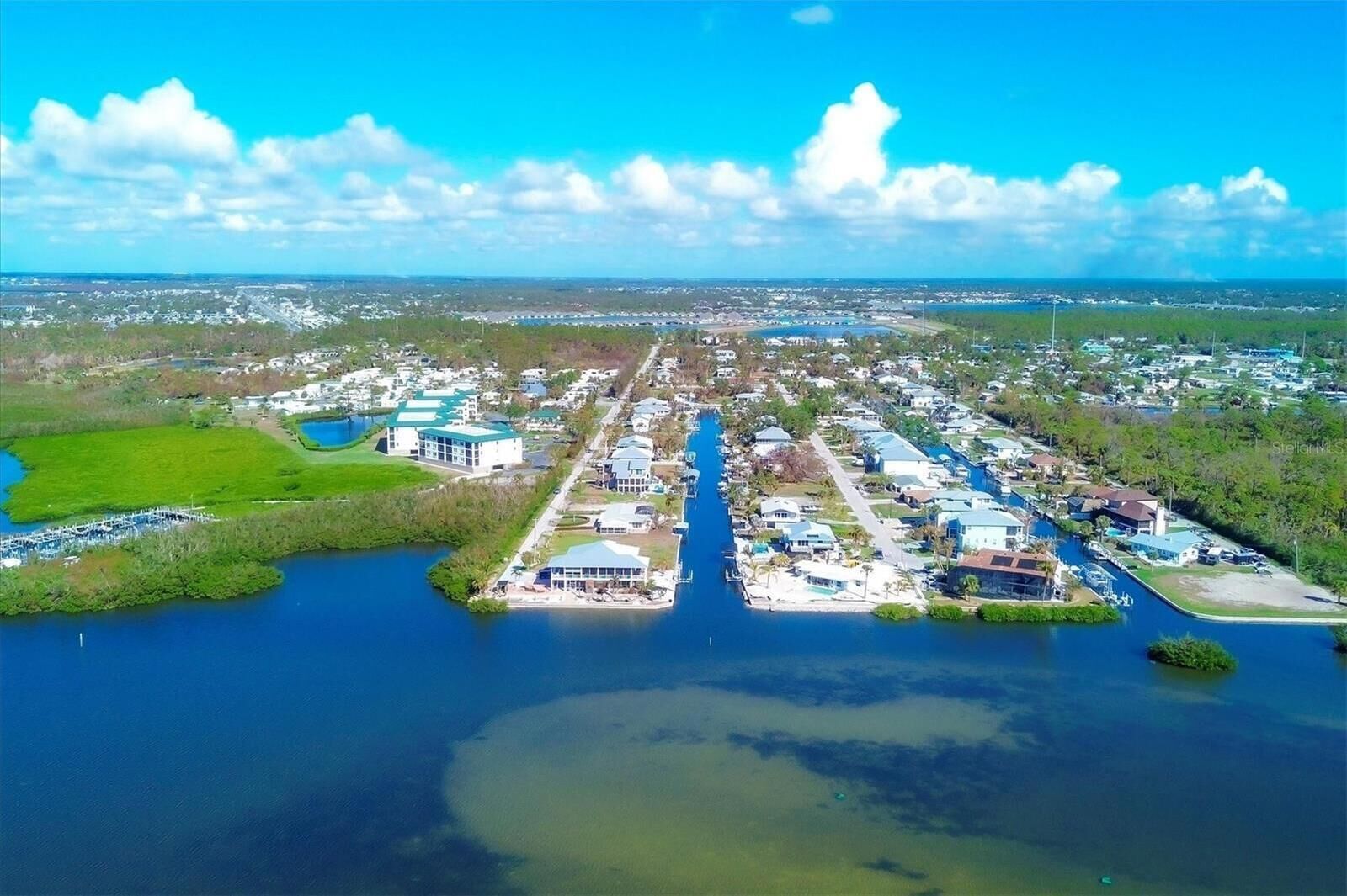 An aerial view of a coastal residential area with a marina, houses, and a large body of water.
