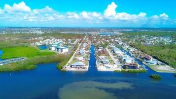 An aerial view of a coastal residential area with a marina, houses, and a large body of water.