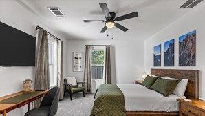A bedroom with a bed, a desk, a chair, a ceiling fan, and a window. - Cozy & Bright 2BR Home - 10 Min to Downtown (Houston)