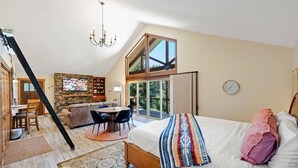 Um amplo quarto no estilo loft, com cama grande, área de jantar e cozinha.