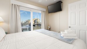 Une chambre d’hôtel dotée d’un grand lit, d’un téléviseur à écran plat fixé au mur, d’un balcon offrant une vue sur les bâtiments et d’une porte avec une poignée.