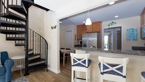 Une cuisine moderne dotée d’un réfrigérateur en acier inoxydable, de meubles en bois et d’un plan de travail en granit.