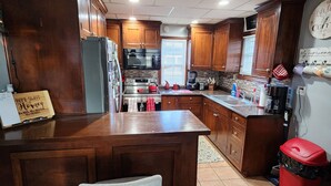 A kitchen with wooden cabinets, a central island, a microwave, and a sink.