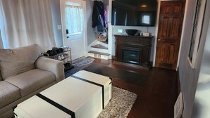 A living room with a sofa, a coffee table, a TV, and a fireplace.