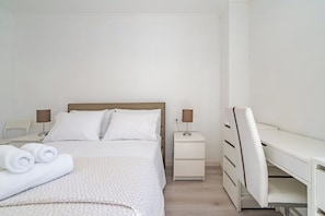 A hotel room with a bed, a desk, and a chair.