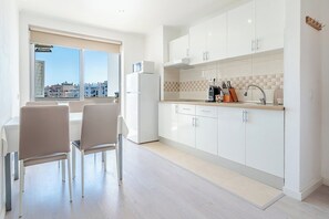 A modern kitchen with white cabinets, a countertop, and a window overlooking a cityscape.