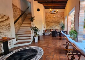 Ein großzügiger Innenbereich mit Pool, Treppe und einer Sitzecke mit Sofa und Sesseln.