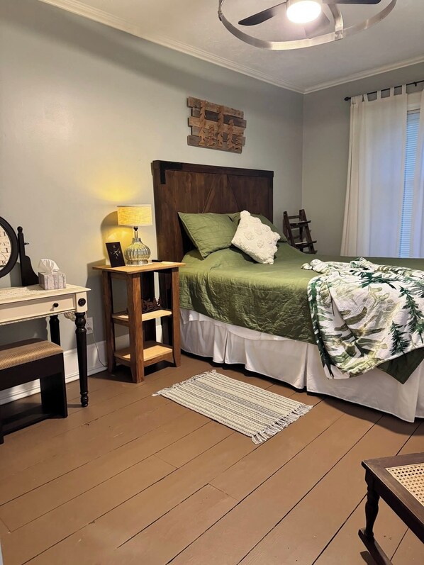 Un dormitorio con cama, mesita de noche, lámpara y una pequeña silla de madera.