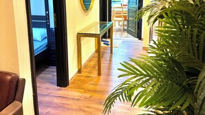 A hallway with a wooden floor, a glass table, and a large potted plant. - Happy Hostel Dubai (Dubai)