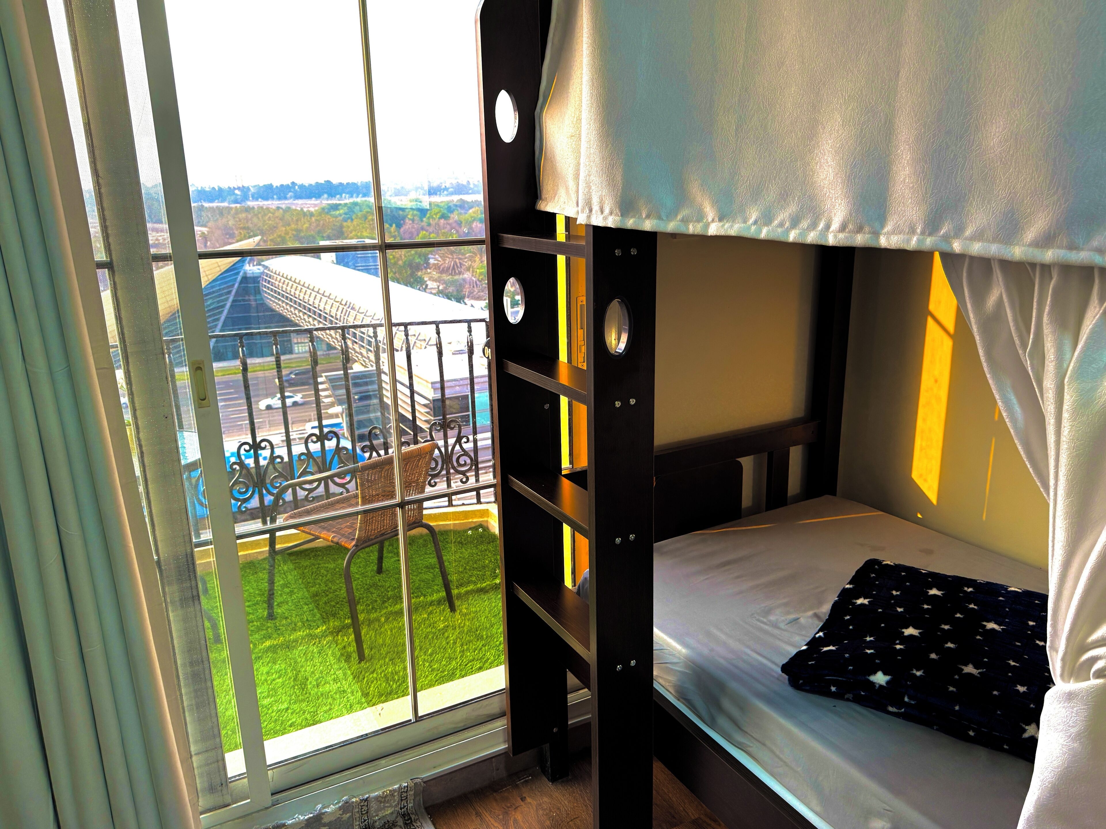 A bunk bed with a view of a parking lot and a building through a window.