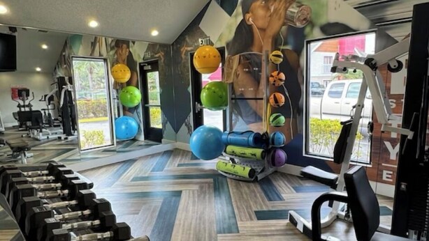 Une salle de sport équipée de matériel d’exercice, ornée d’une fresque murale et dotée d’une fenêtre donnant sur l’extérieur.
