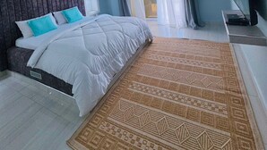 Ein Schlafzimmer mit einem Bett, Deckenventilator, einem Fenster mit Vorhängen und einem Fernseher auf einem Schrank.