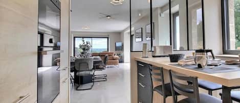 A modern kitchen with a central island, a dining area with a view, and a large window.