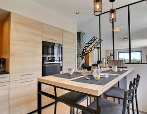 A modern kitchen with a built-in oven and a dining area with a long table and chairs.