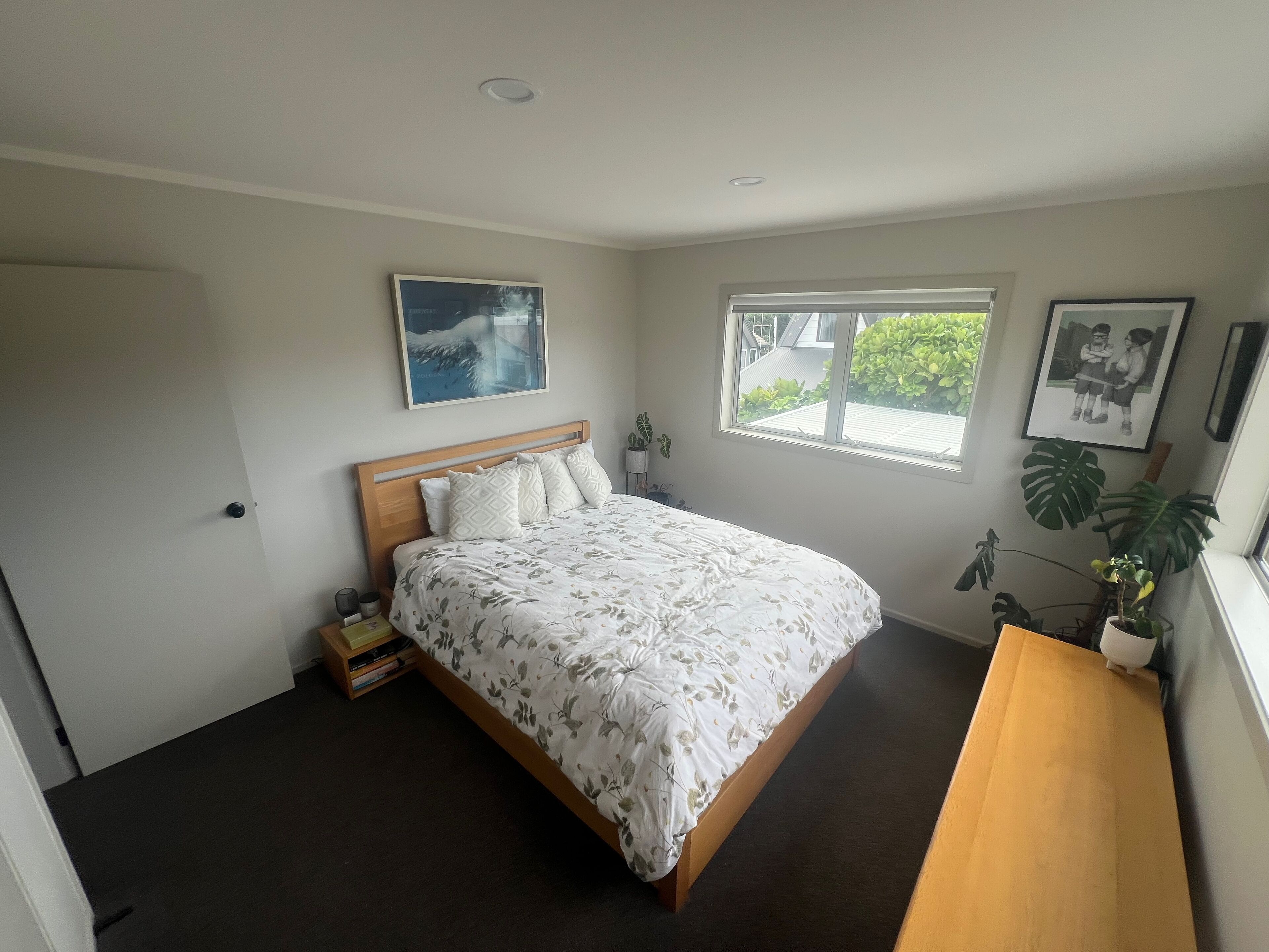Une chambre à coucher avec un lit, une fenêtre, une table de chevet et une plante.