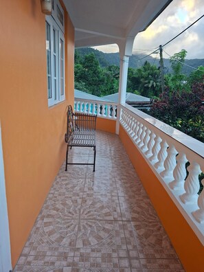 A balcony with a patterned floor, a metal chair, and a white balustrade.