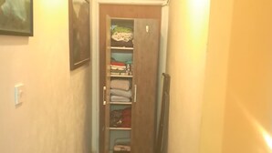 Un pasillo con piso de baldosas, un equipo de aire acondicionado en la pared y una puerta que da a una habitación con armario.