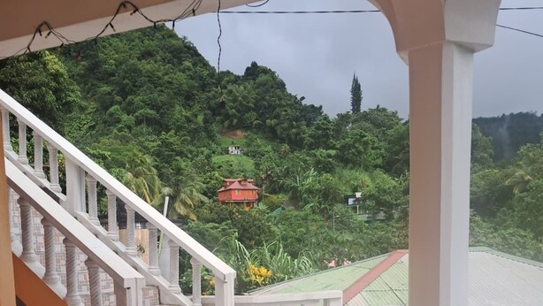 Un balcón con vistas a una ladera verde exuberante y una piscina.