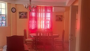 Ein Essbereich mit Tisch, Stühlen, einer Chandelüster und einem Fenster mit Vorhängen.