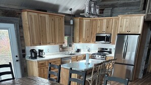 A spacious kitchen with wooden cabinets, a stainless steel refrigerator, and a large dining table with benches. - Secluded with amazing view (Jackson)
