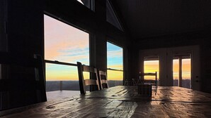 A spacious room with large windows, wooden flooring, and a view of the sunset. - Secluded with amazing view (Jackson)