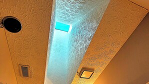 A bathroom with a textured ceiling, a shower area, and a door with a towel rack. - Cozy and Bright Retreat Near Raleigh Hotspots (Raleigh)