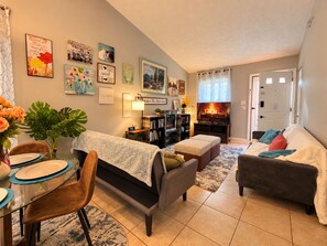 A cozy living room with a fireplace, comfortable seating, and a dining area with a glass table. - Cozy Quiet North Raleigh Retreat/Private Deck. Dog-Friendly! (Raleigh)