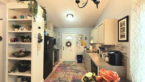 A kitchen with white cabinets, a black refrigerator, a coffee maker, and a colorful rug. - Cozy and Bright Retreat Near Raleigh Hotspots (Raleigh)