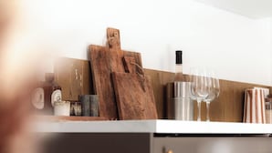 A modern kitchen with a wooden cutting board, wine glasses, and a stainless steel container.