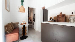 A compact kitchen with modern appliances, a dining area with a round table, and a cozy seating area with a sofa.