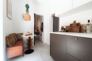 A compact kitchen with modern appliances, a dining area with a round table, and a cozy seating area with a sofa.