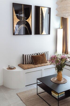 A modern living room with a white sofa, a black coffee table, and two abstract wall art pieces.