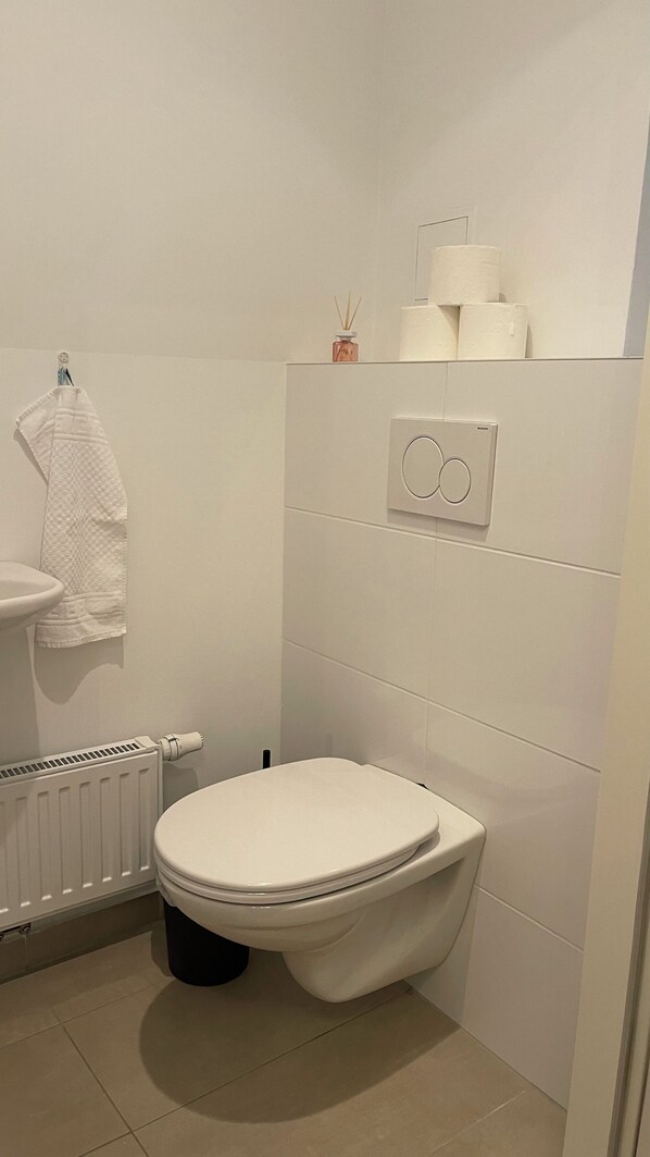 Une salle de bain moderne équipée de toilettes, d’un lavabo et d’un porte-serviettes.
