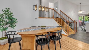 Una cocina moderna con una isla de madera, sillas negras y una escalera con barandillas de madera.