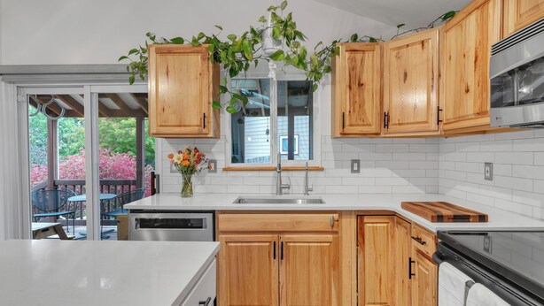 Una cocina moderna con armarios de madera, encimera blanca y campana extractora de acero inoxidable.