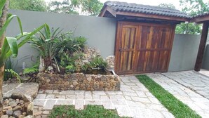 Ein Garten mit einer Steinmauer, einem hölzernen Tor und einem Baum.