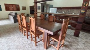 Ein Essbereich mit Holztisch und -stühlen, im Hintergrund eine Küche und ein Fliesenboden.