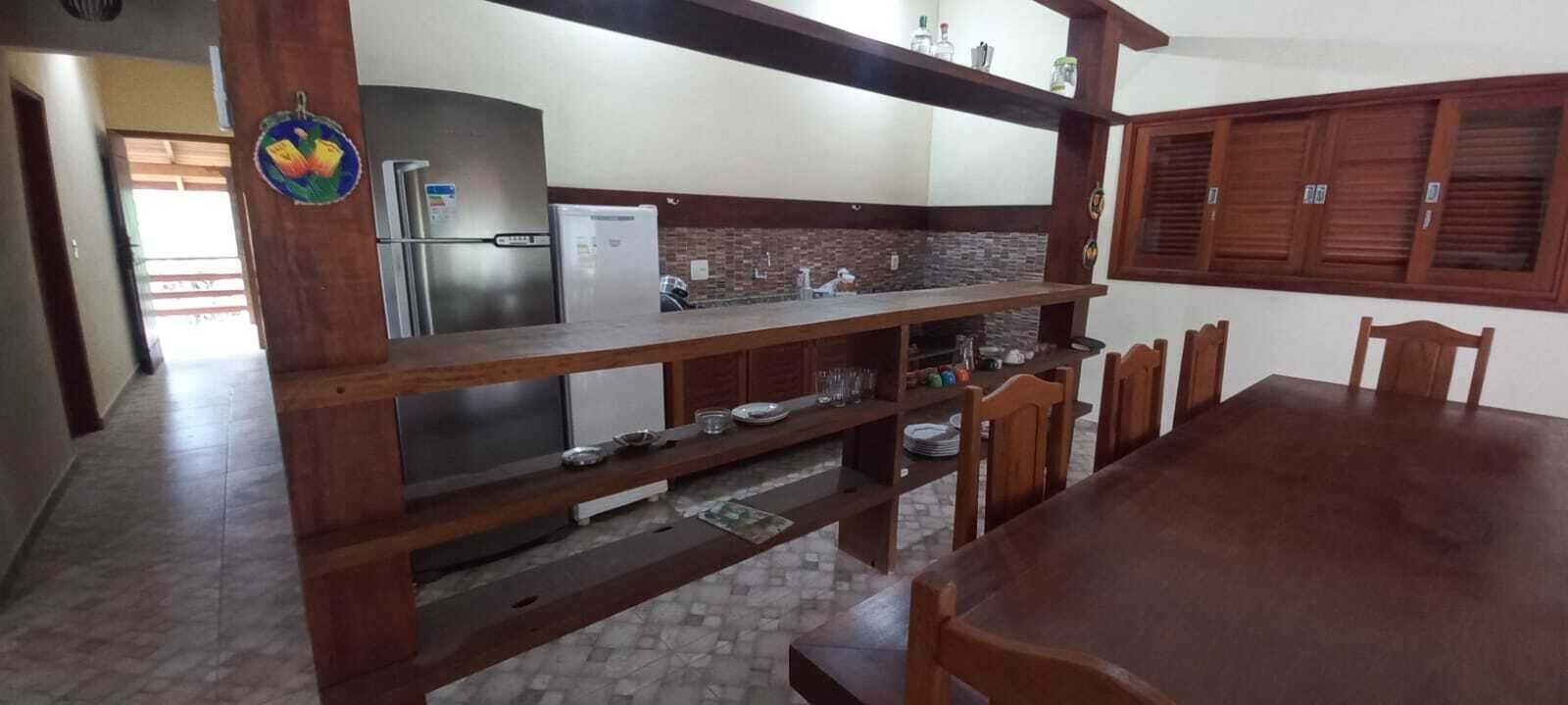 A kitchen with a wooden countertop, a refrigerator, and a dining area with chairs and a table.