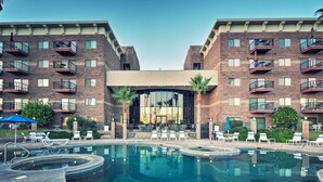 Um hotel com piscina, várias varandas e áreas de estar ao ar livre.