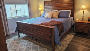 Una camera da letto con un letto in legno, due abat-jour, un comodino e una ventola a soffitto.