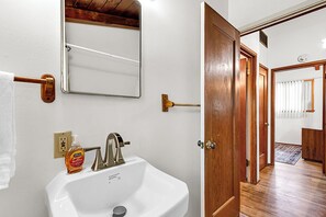 A bathroom with a white sink, a mirror, and a towel rack. - 2BR Cozy Cabin Vibes | King Bed + Vaulted Ceilings (Cheyenne)