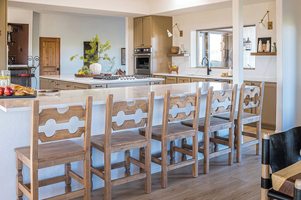 A modern kitchen with wooden chairs, a central island, and a dining area.