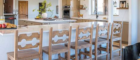 A modern kitchen with wooden chairs, a central island, and a dining area.