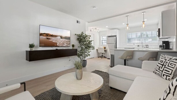 A modern living room with a flat-screen TV, a round wooden coffee table, and a sofa. - Luxury apt w/ FREE parking, crib, prime location (Tampa)