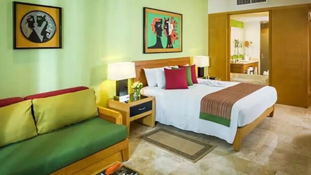 A hotel room with a bed, green sofa, nightstands, and artwork on the walls. - New Year's- Dec 27th-Jan 3/2026- Luxury Resort- 2BR Grand Mayan Playa del Carmen (Solidaridad)