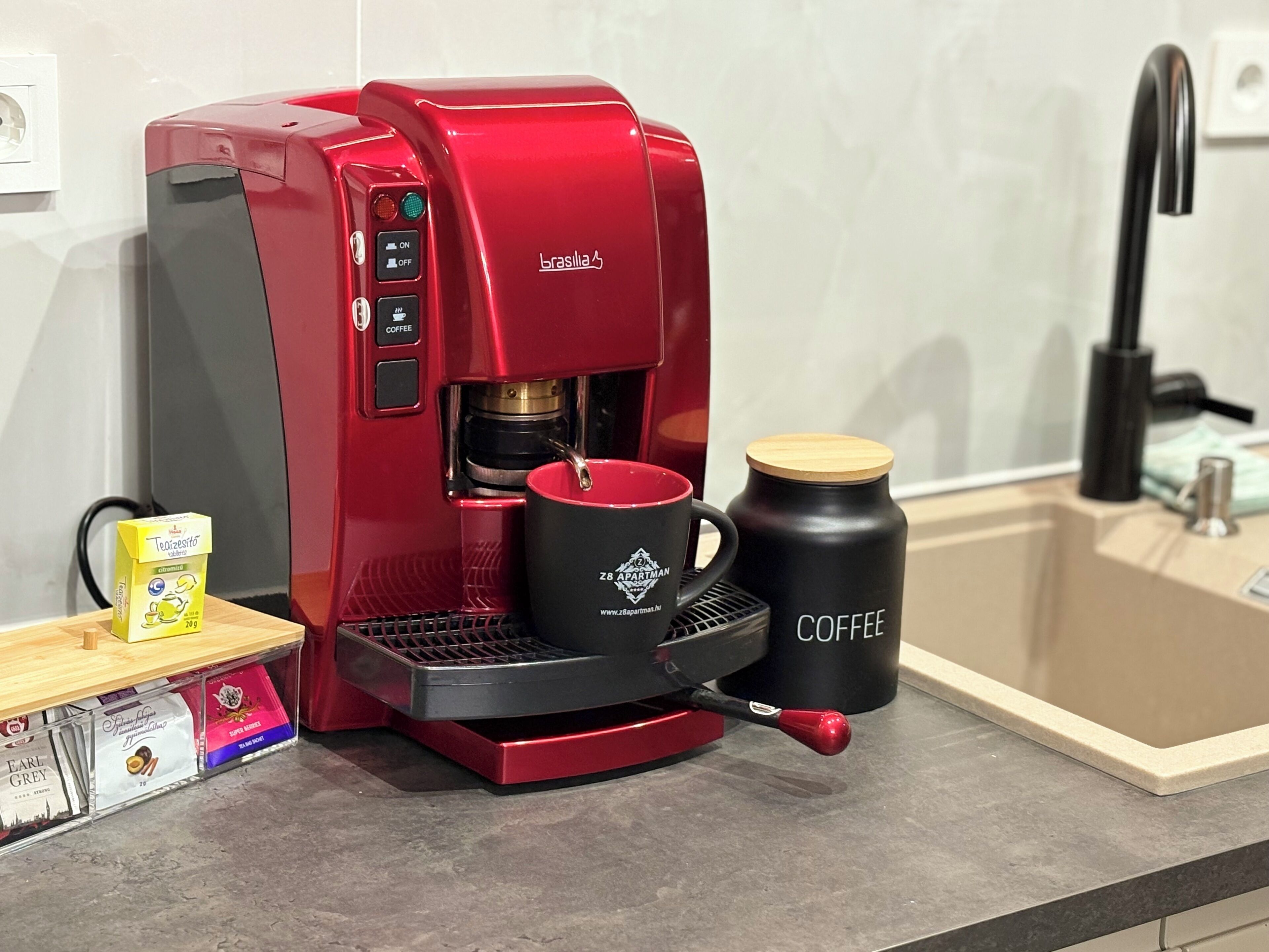 A red coffee maker with a coffee mug and a thermos on a countertop.