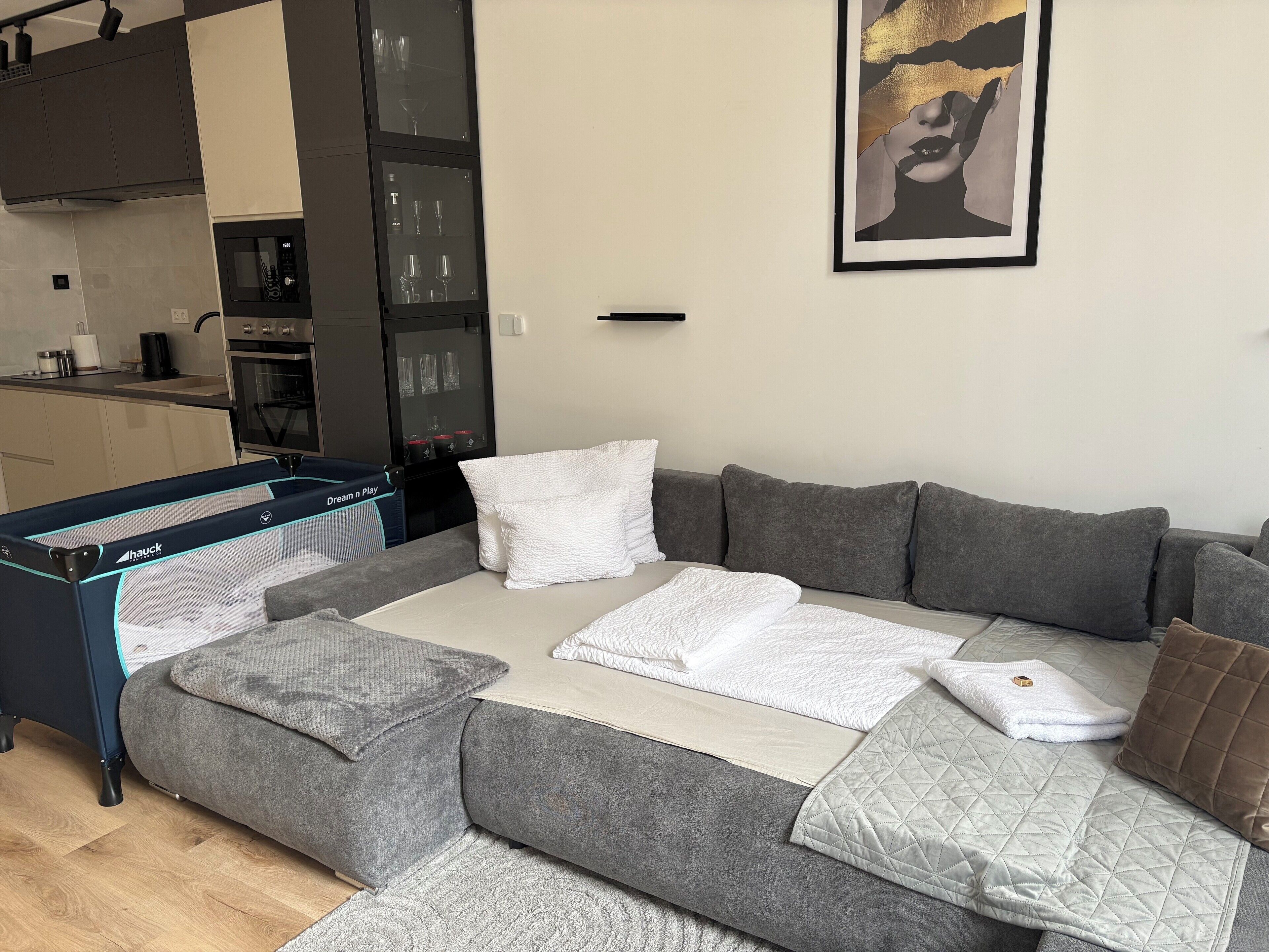 Una sala moderna con un sofá seccional gris, un edredón blanco acolchado y una alfombra gris.