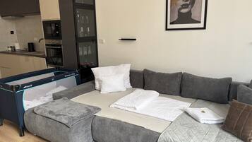 Una sala moderna con un sofá seccional gris, un edredón blanco acolchado y una alfombra gris.